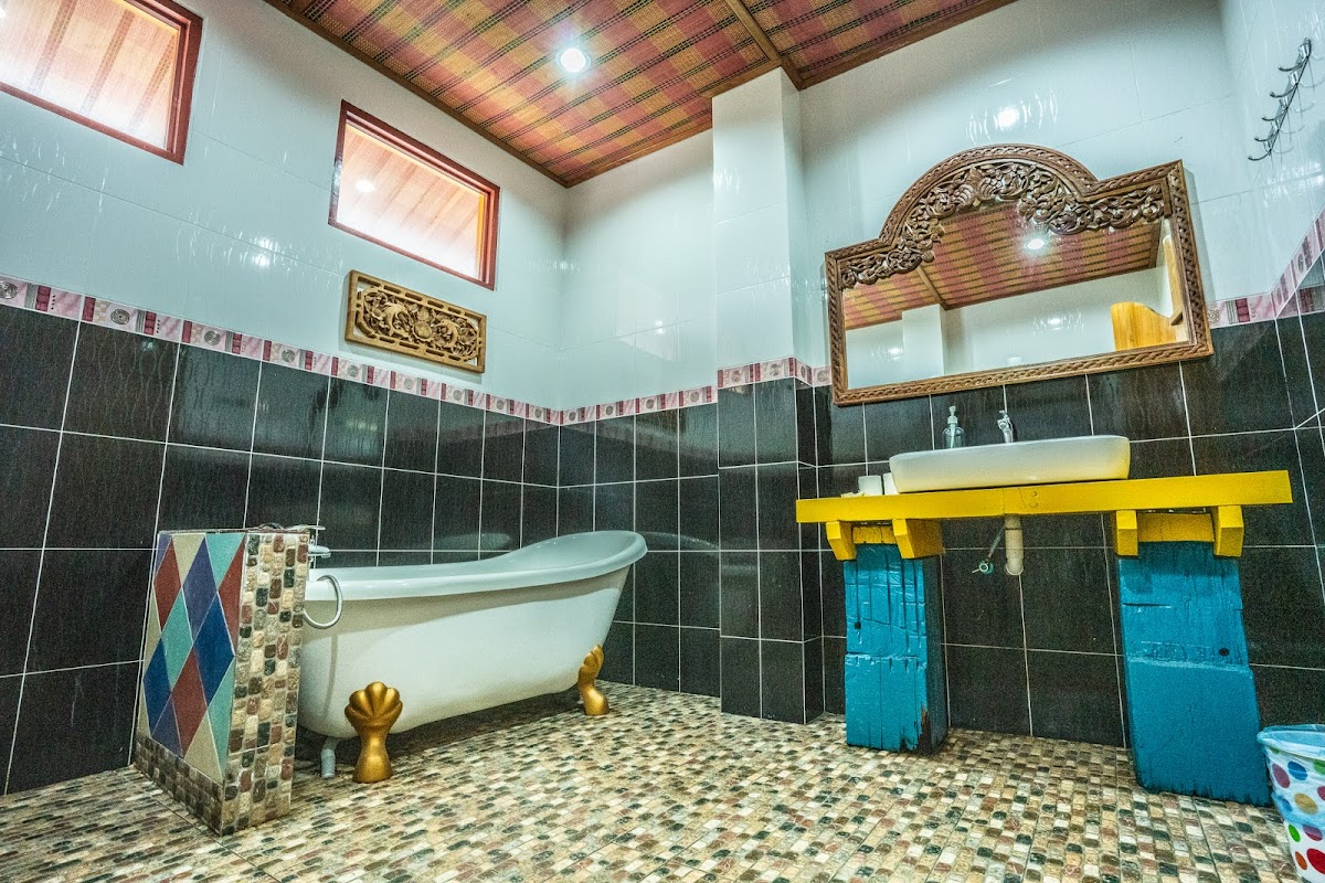 A vivid bathroom with a white clawfoot tub, mosaic floor and yellow-and-turquoise carved vanity