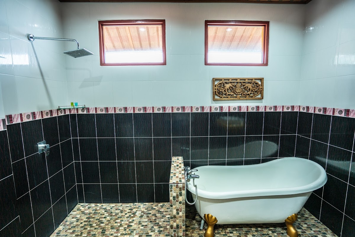 An ensuite with a clawfoot soaking tub, rain shower and mosaic-tiled platform